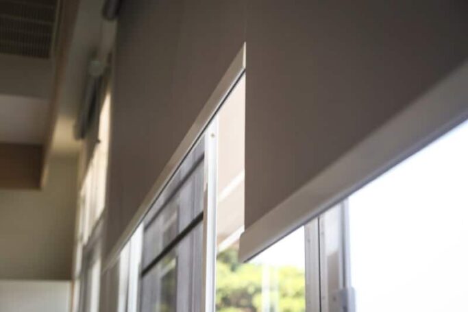 Roller shades cover the top half a glass window.